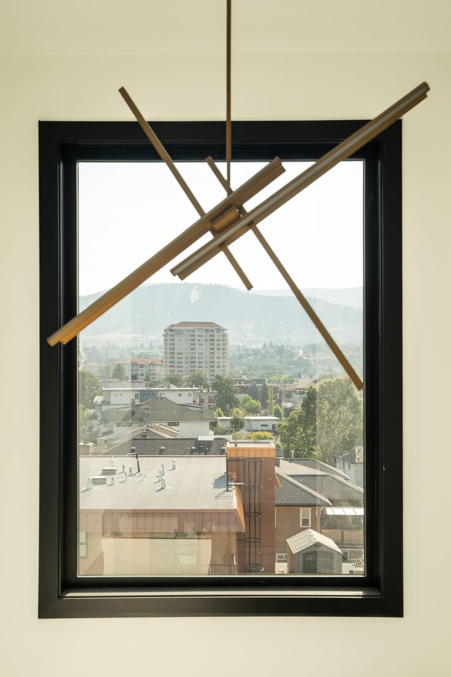 Brass linear light fixture in front of a window framing the Okanagan hills
