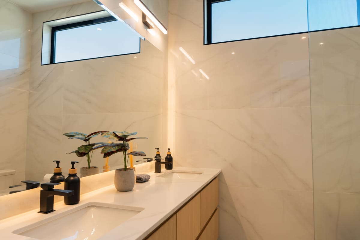 Marble ensuite with a long vanity and a high clerestory window