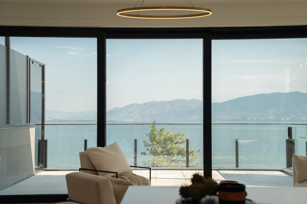 Living room with floor-to-ceiling glass opening onto a balcony above Okanagan Lake