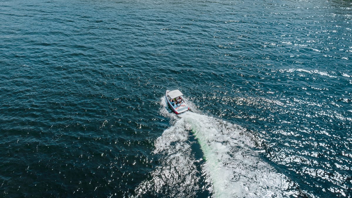 A single boat crossing deep blue water on Okanagan Lake, seen from above