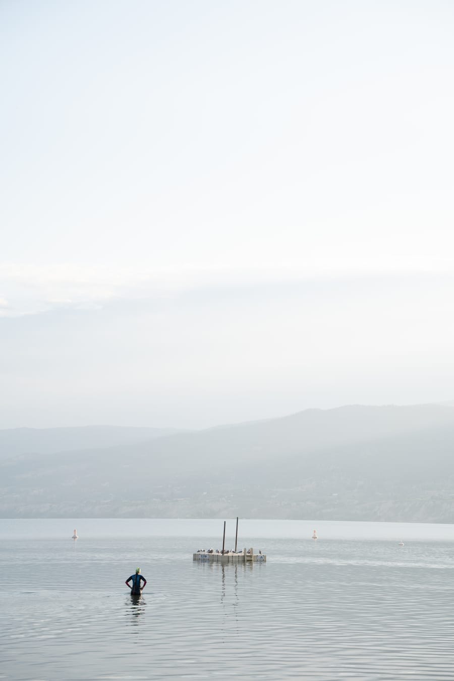A swimmer wading out toward a floating dock on Okanagan Lake